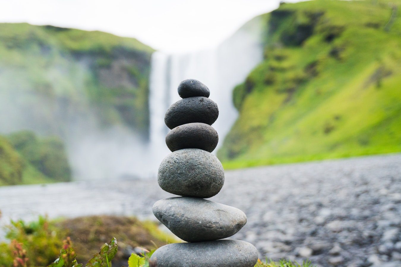 A stack of balanced stones in front of a waterfall