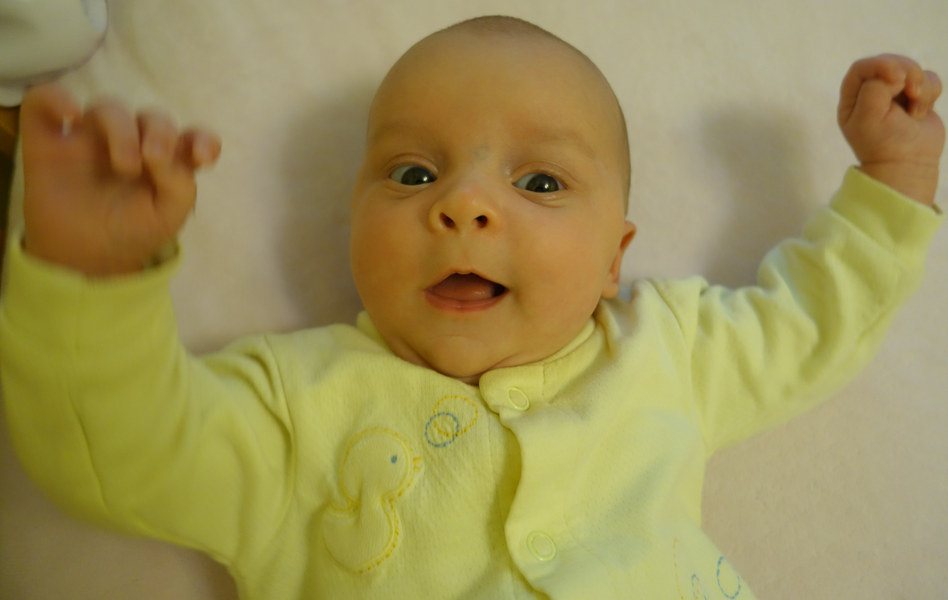 A baby lying on their back, arms raised